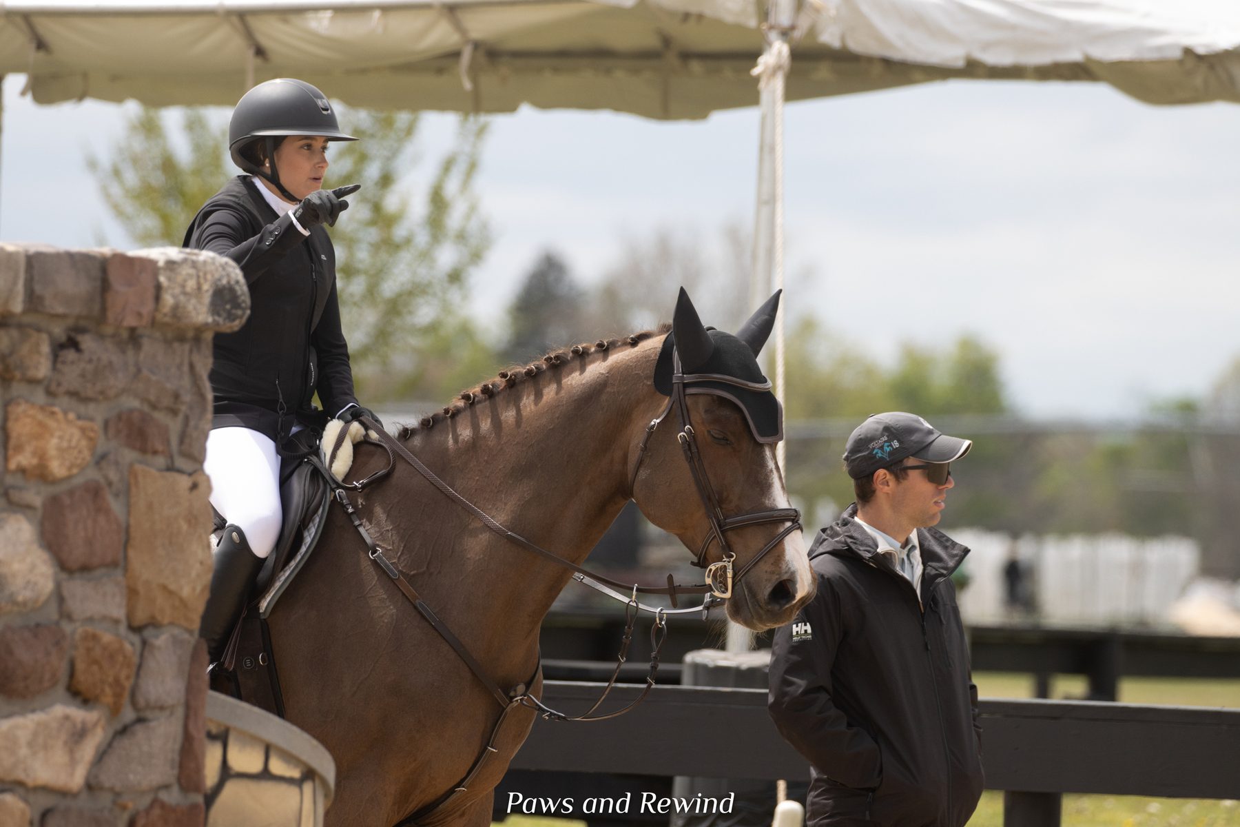 A junior rider on a chestnut horse receiving instruction from Kyle Gambino at a show ring in Brewster, NY